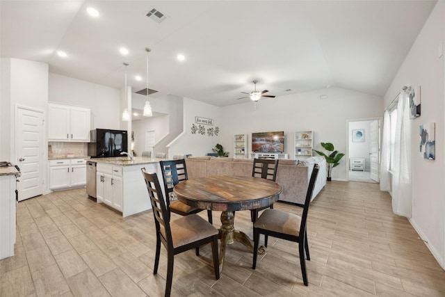 dining room with a ceiling fan, wood finish floors, visible vents, and vaulted ceiling