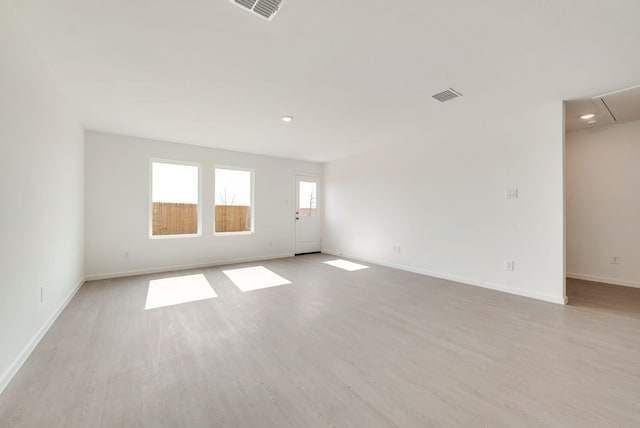 unfurnished room with light wood finished floors, attic access, and visible vents