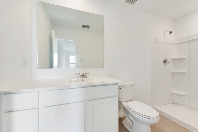 bathroom featuring visible vents, a shower, toilet, wood finished floors, and vanity