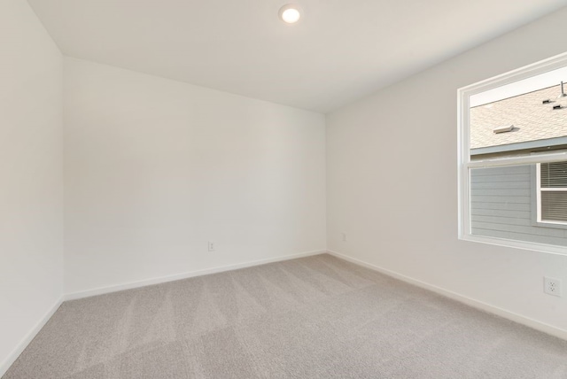 spare room featuring recessed lighting, baseboards, and light colored carpet