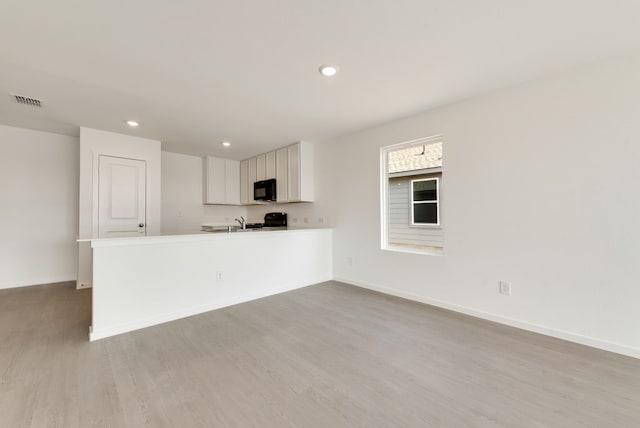 kitchen with white cabinetry, visible vents, baseboards, light wood-type flooring, and black appliances