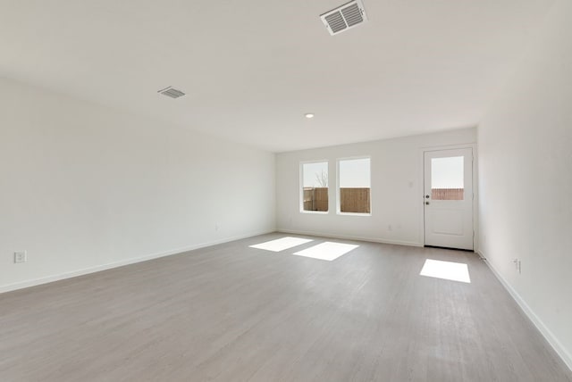 spare room with visible vents, baseboards, and wood finished floors