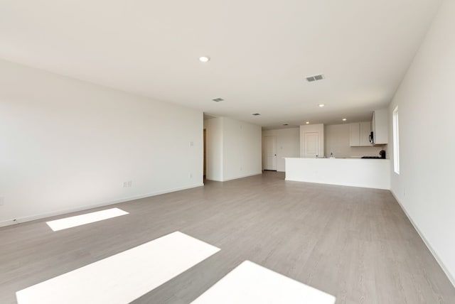 unfurnished living room featuring light wood-type flooring, visible vents, baseboards, and recessed lighting