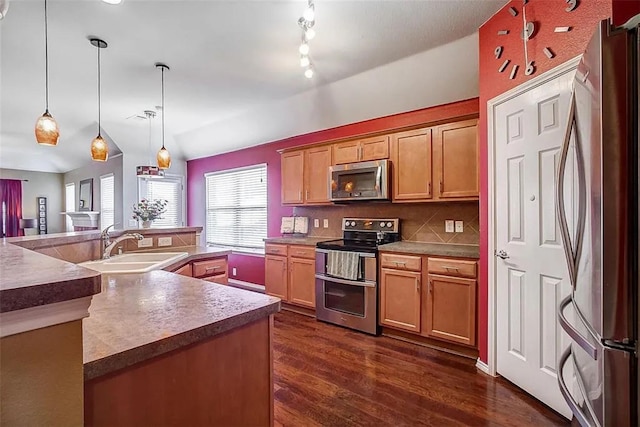 kitchen with pendant lighting, dark wood finished floors, decorative backsplash, appliances with stainless steel finishes, and a sink