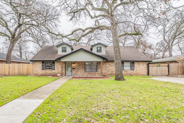 view of front of house with a front lawn, a shingled roof, fence, and brick siding