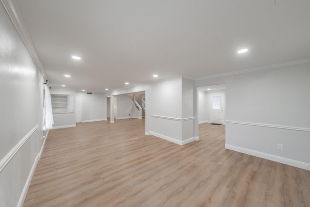 below grade area with ornamental molding, light wood-type flooring, and stairway