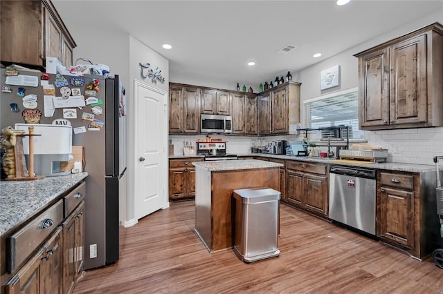 kitchen with visible vents, decorative backsplash, light wood-style flooring, a kitchen island, and stainless steel appliances