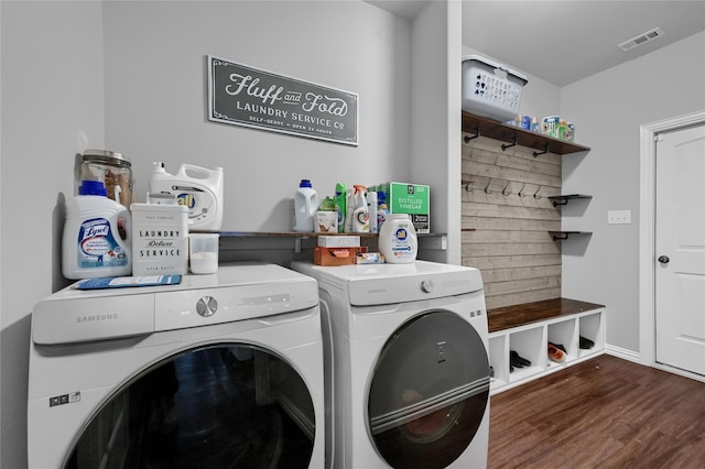 clothes washing area featuring laundry area, wood finished floors, washing machine and dryer, and visible vents