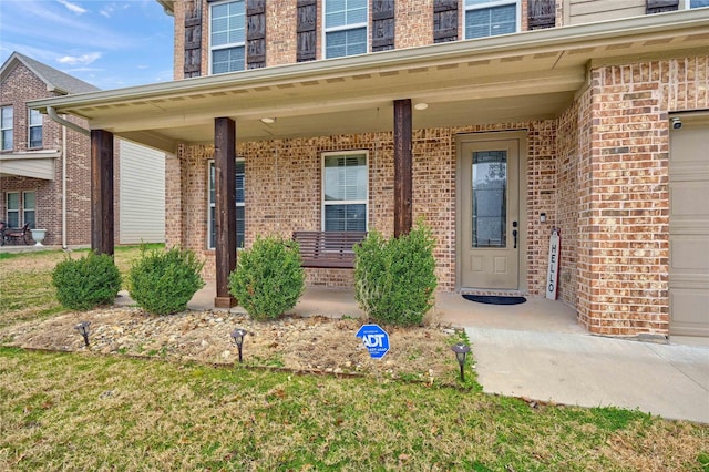 property entrance with a porch, brick siding, and a garage