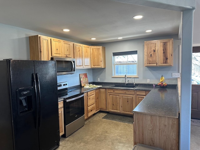 kitchen featuring dark countertops, recessed lighting, light brown cabinetry, appliances with stainless steel finishes, and a sink