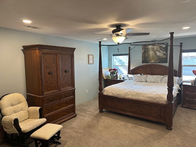 bedroom featuring light carpet, ceiling fan, multiple windows, and visible vents