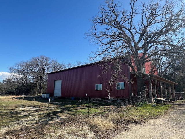 view of property exterior with a pole building, a detached garage, fence, and an outbuilding