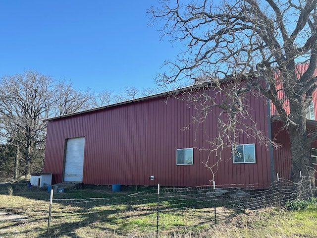 view of property exterior with an outbuilding and fence