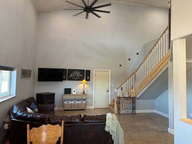 living area featuring a high ceiling, stairway, a ceiling fan, and baseboards