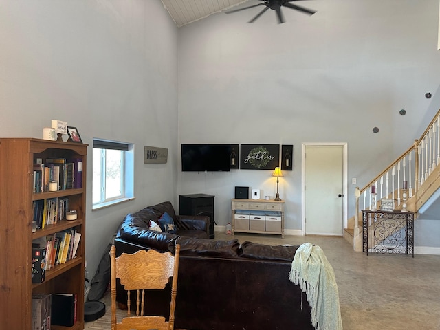 living room featuring a ceiling fan, high vaulted ceiling, concrete floors, baseboards, and stairs