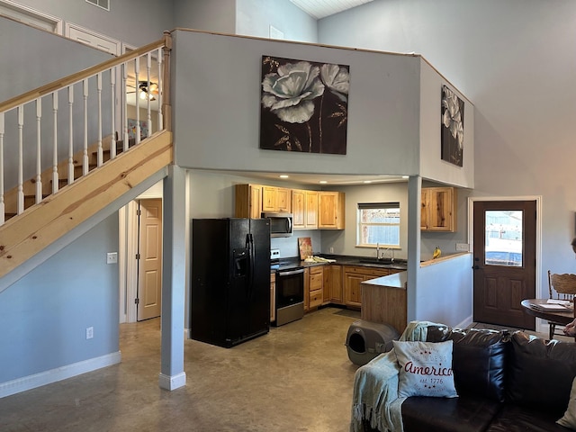 kitchen with dark countertops, appliances with stainless steel finishes, a sink, high vaulted ceiling, and baseboards