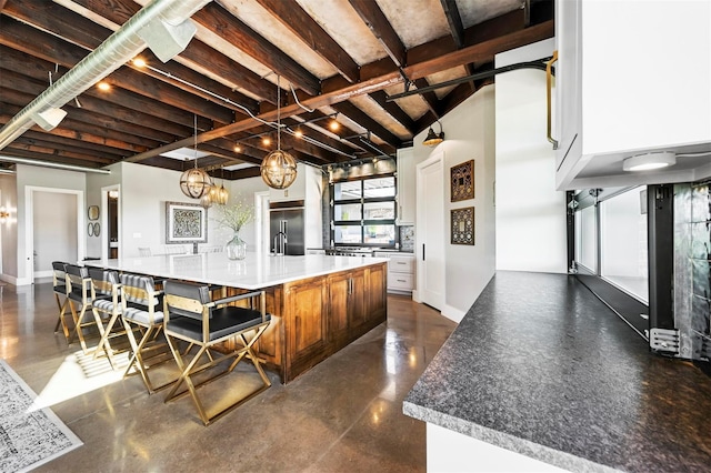 kitchen with hanging light fixtures, a large island, stainless steel built in refrigerator, and concrete flooring