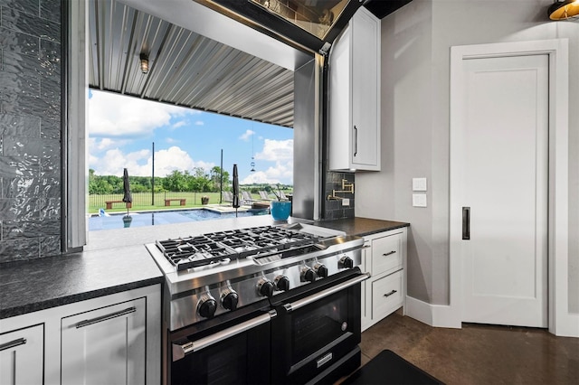 kitchen with concrete flooring, dark countertops, white cabinets, and double oven range