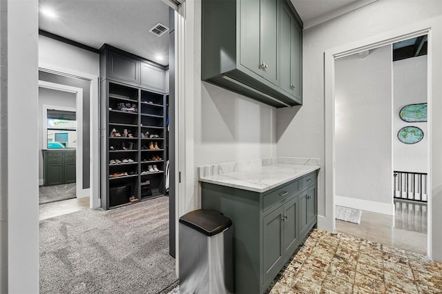 kitchen with light stone counters, light carpet, visible vents, baseboards, and gray cabinets