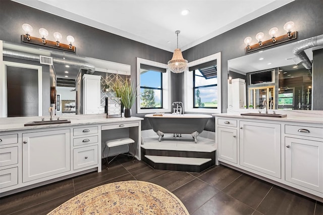 full bathroom with a soaking tub, visible vents, two vanities, and a sink