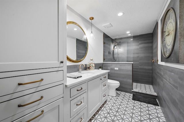 bathroom with tile walls, recessed lighting, toilet, vanity, and walk in shower