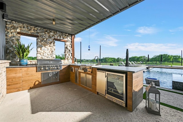 view of patio featuring wine cooler, a pool, an outdoor kitchen, a sink, and a grill