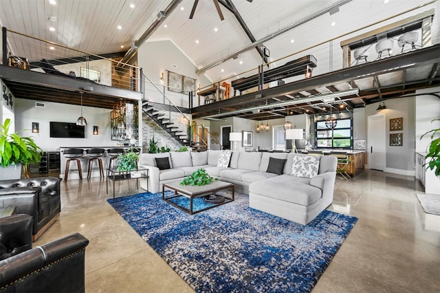 living room featuring concrete flooring, high vaulted ceiling, recessed lighting, a notable chandelier, and stairway