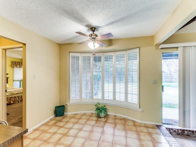 unfurnished dining area featuring ceiling fan, a textured ceiling, and baseboards