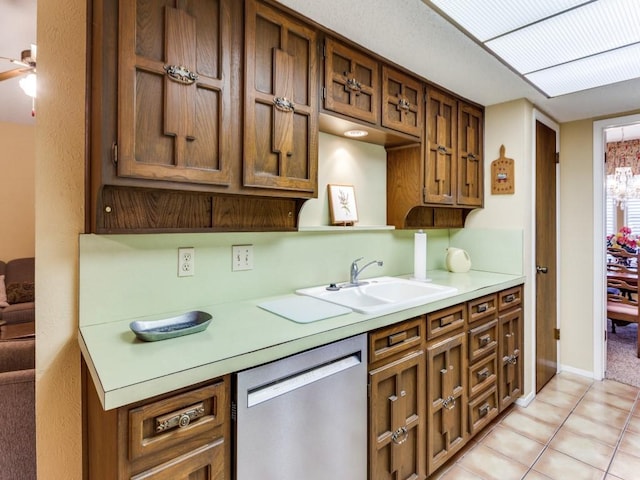 kitchen featuring light countertops, stainless steel dishwasher, brown cabinetry, and a sink