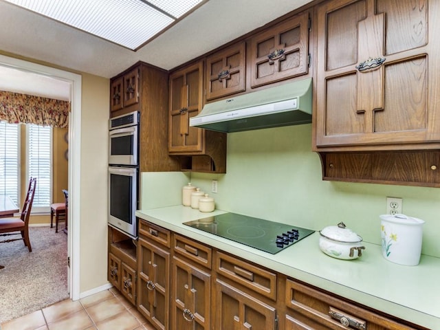 kitchen with light carpet, black electric cooktop, stainless steel double oven, light countertops, and under cabinet range hood