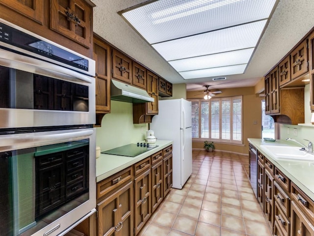 kitchen with light countertops, appliances with stainless steel finishes, a sink, and under cabinet range hood