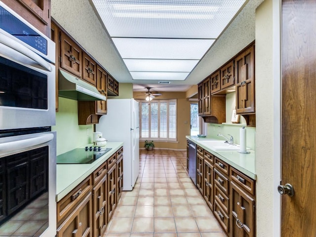 kitchen featuring stainless steel appliances, light countertops, a ceiling fan, a sink, and under cabinet range hood