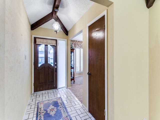 foyer entrance featuring vaulted ceiling with beams, brick floor, a textured ceiling, and a textured wall