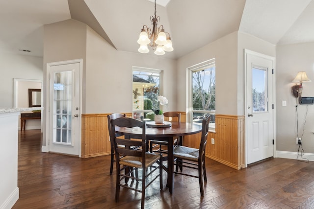 dining area with vaulted ceiling, a notable chandelier, dark wood-style floors, and wainscoting