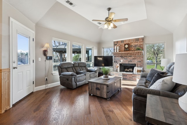 living room featuring baseboards, visible vents, lofted ceiling, dark wood-style flooring, and a brick fireplace