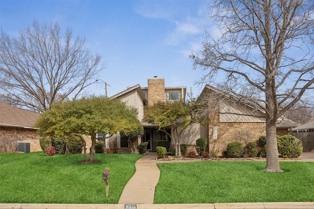 mid-century inspired home featuring brick siding, a front lawn, and a chimney