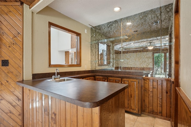 bar featuring light tile patterned floors, a textured ceiling, and a sink