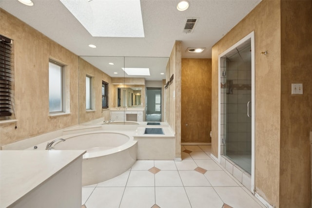 bathroom with a skylight, a garden tub, visible vents, a stall shower, and vanity