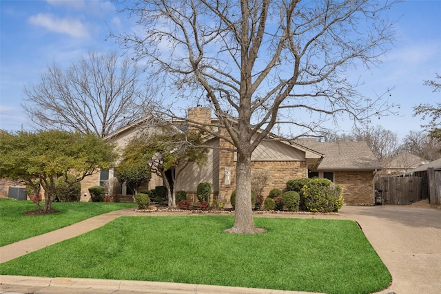 view of front of property featuring driveway, a chimney, a front lawn, and brick siding