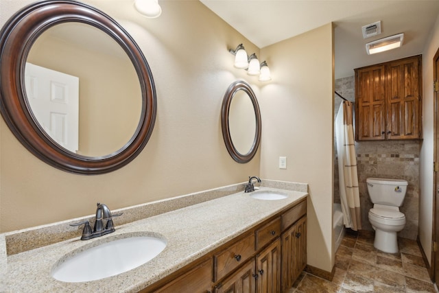 bathroom featuring visible vents, a sink, toilet, and double vanity