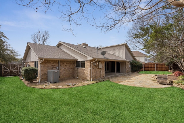 back of house with central AC unit, a chimney, a yard, a patio area, and brick siding