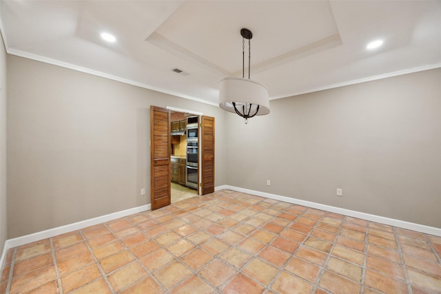 empty room with a raised ceiling, visible vents, and crown molding