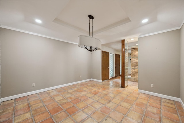 spare room with baseboards, a raised ceiling, and crown molding