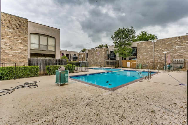 pool with a patio area and fence