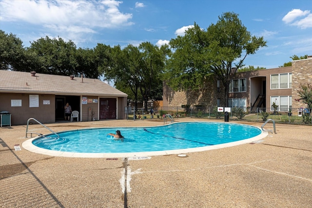 pool featuring cooling unit, fence, and a patio