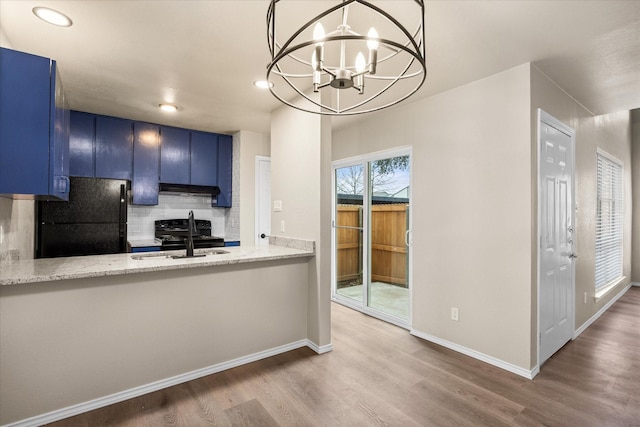 kitchen with blue cabinets, wood finished floors, a sink, backsplash, and black appliances