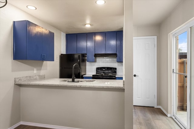 kitchen featuring a sink, black appliances, under cabinet range hood, and blue cabinets