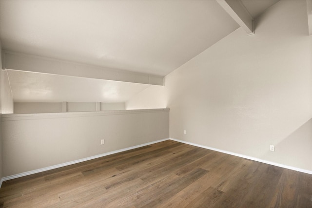 spare room featuring lofted ceiling with beams, baseboards, and wood finished floors