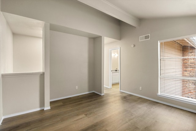 spare room with visible vents, lofted ceiling with beams, baseboards, and wood finished floors