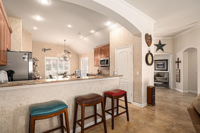 kitchen with arched walkways, lofted ceiling, stainless steel appliances, a kitchen bar, and crown molding